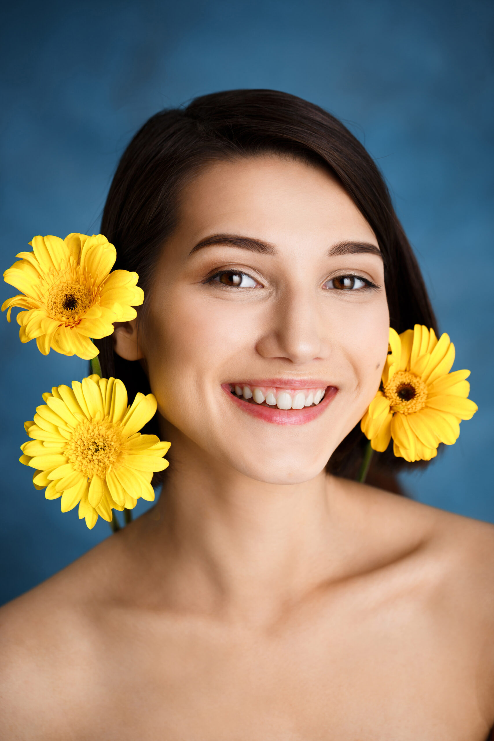 Picture of tender young girl with flowers over blue background